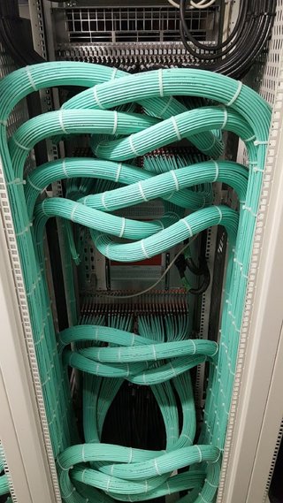 Aqua fiber service loops organized inside a cabinet