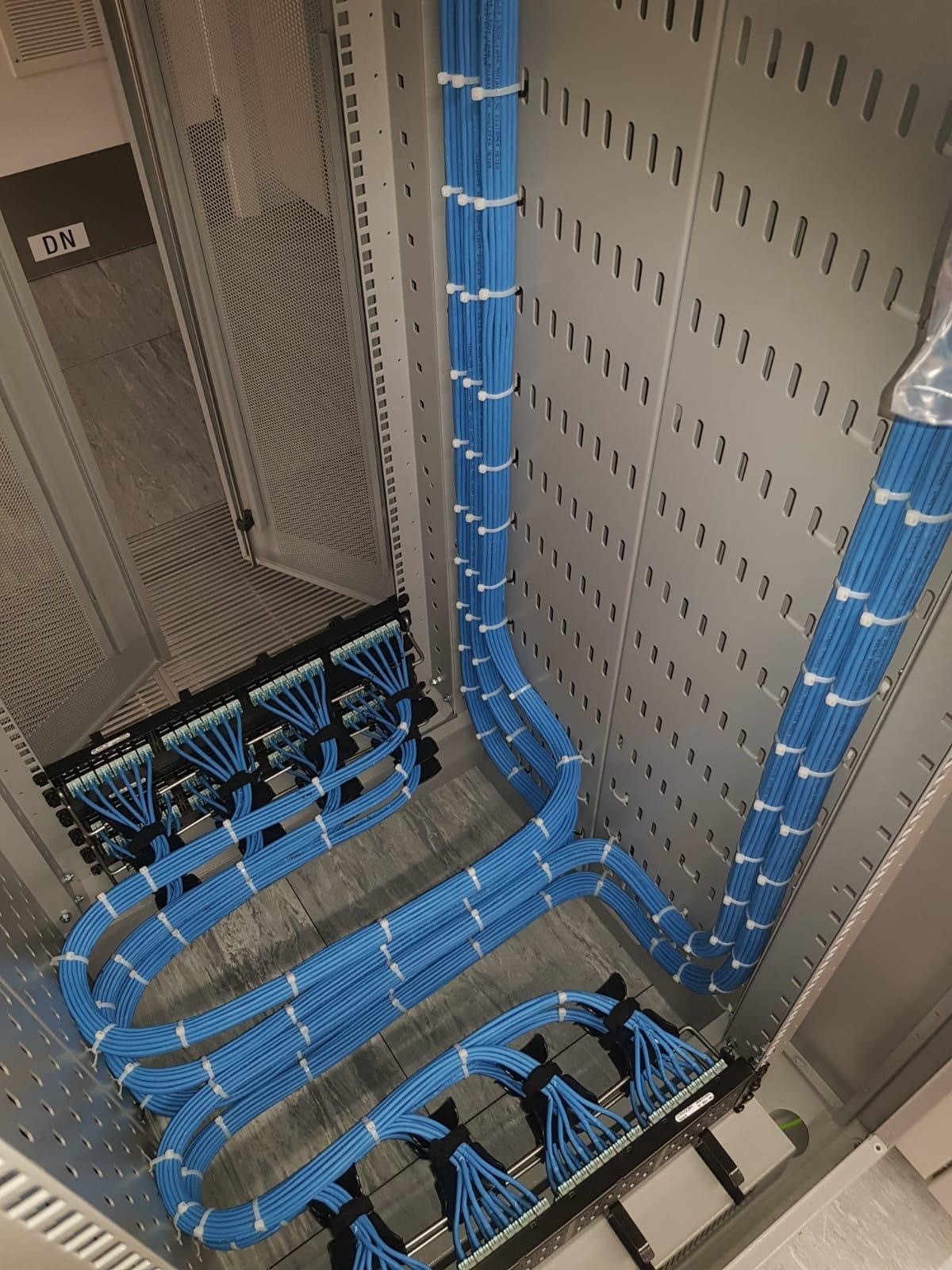 Blue structured cabling routed along a cabinet wall