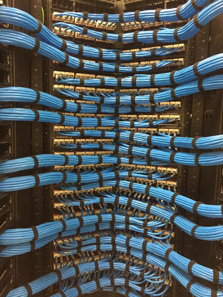 Blue network cables dressed in uniform arcs at patch panels