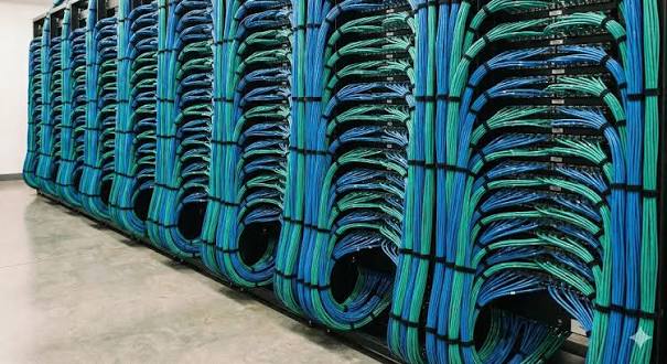 Long row of dense blue and green CAT6 cabling arranged in repeated vertical rack patterns