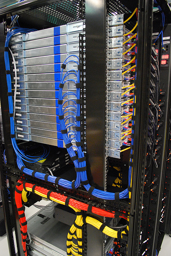 Blue, red and yellow CAT6 cables routed through separate pathways in a network rack