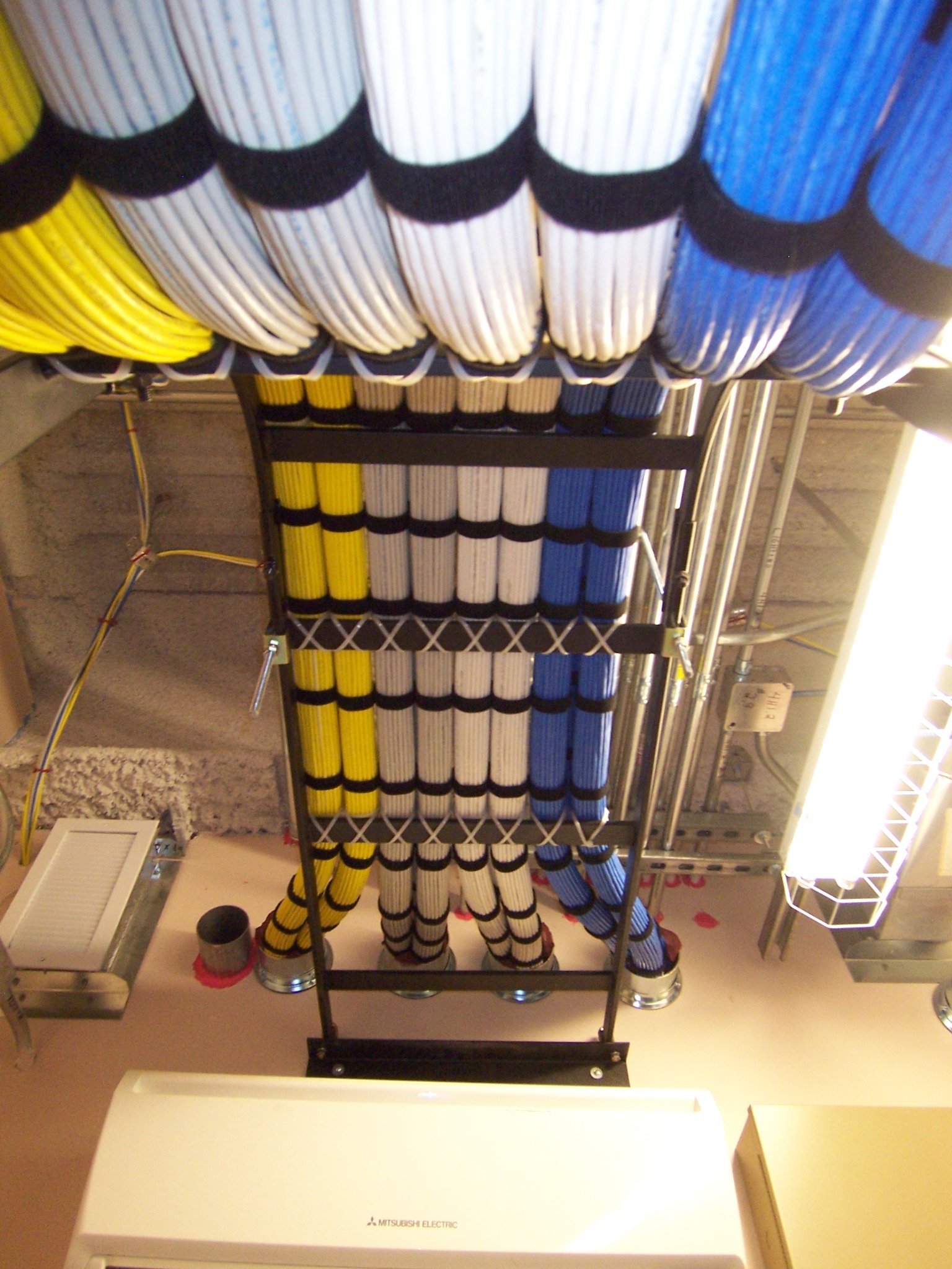Yellow, white and blue cable bundles secured in an overhead pathway