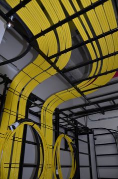 Yellow cables turning from overhead pathways into equipment racks