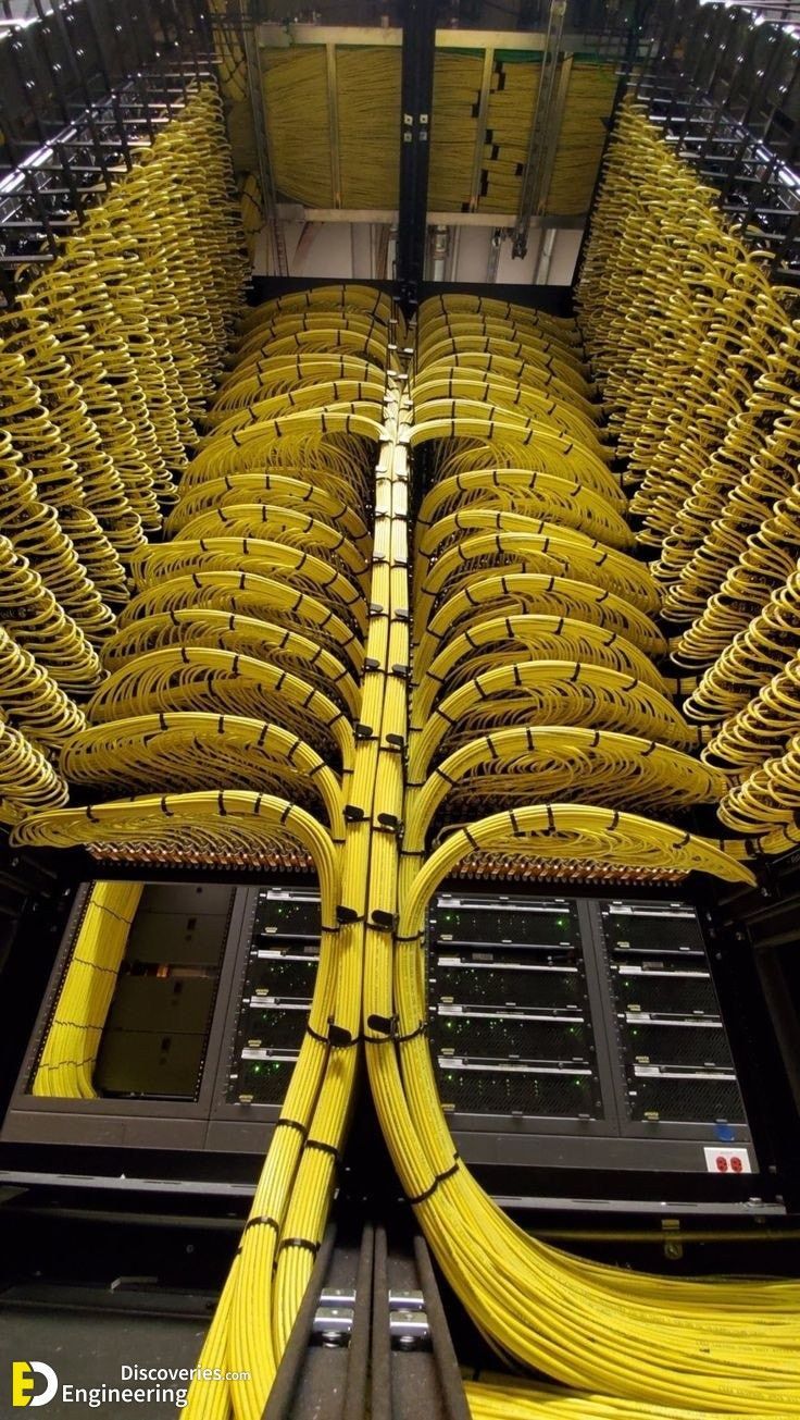 Yellow fiber cable installation branching symmetrically above equipment racks